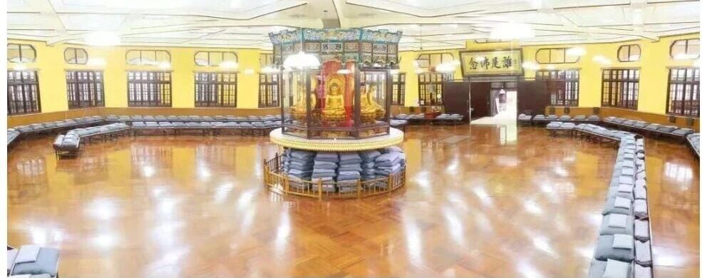 Interior do salão de meditação com almofadas dispostas em círculo em torno de um nicho central dourado