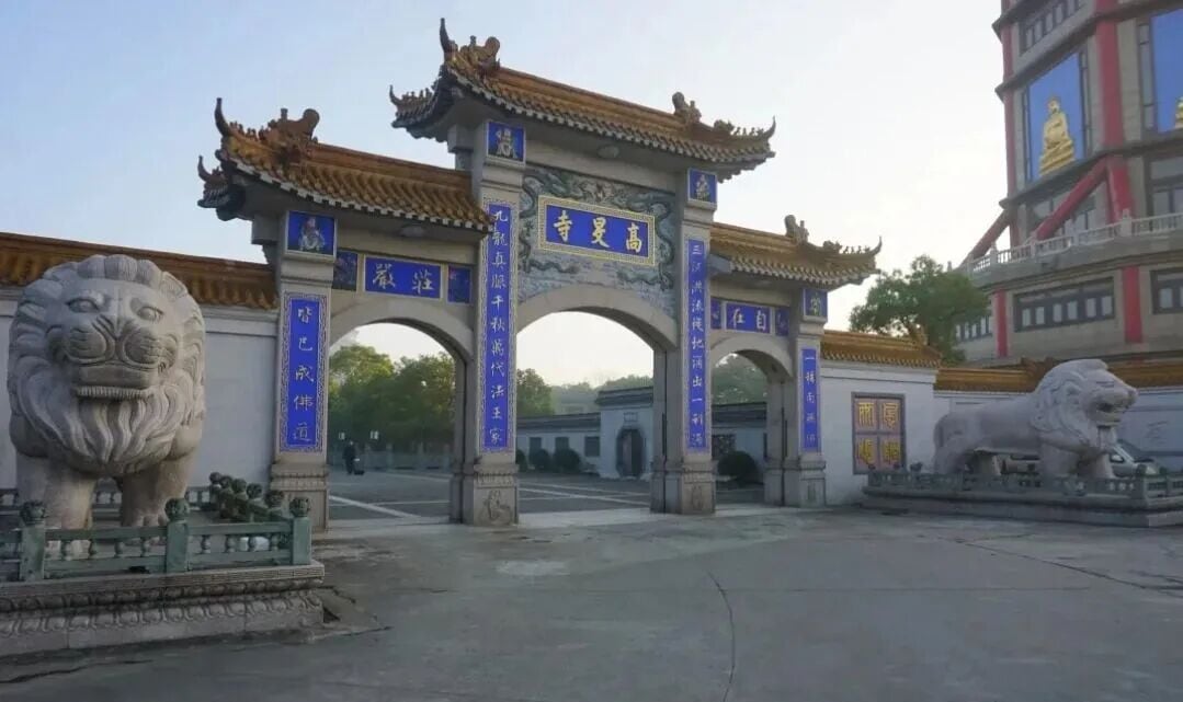 Portal de pedra de três arcos com a placa 高旻寺 e dois leões de pedra na entrada
