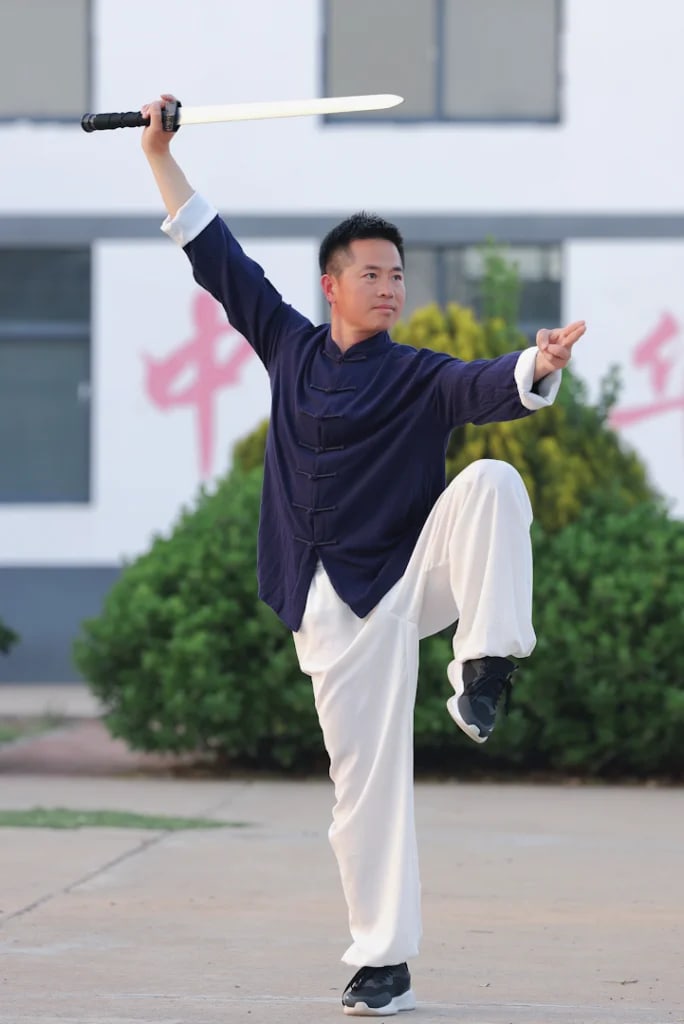 Mestre Bao em postura de espada do estilo Baji, com uma perna erguida
